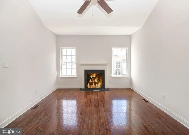 an empty room with wooden floor fireplace and windows