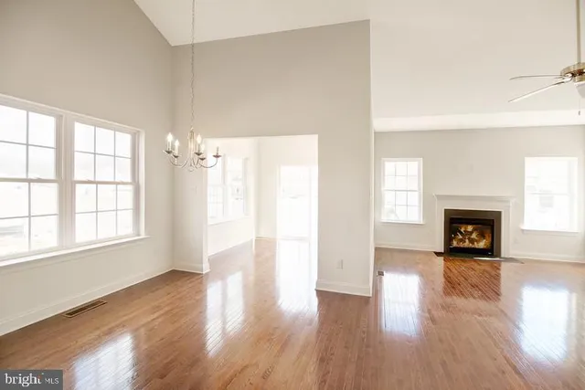 a kitchen with stainless steel appliances granite countertop a refrigerator a sink dishwasher a stove and white countertops with wooden floor