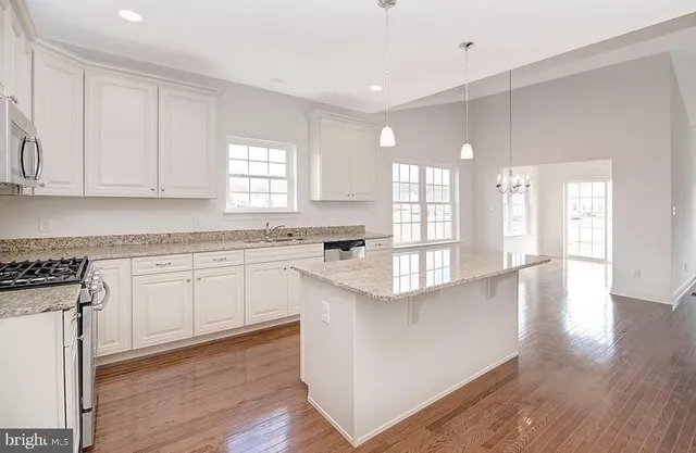 a kitchen with stainless steel appliances granite countertop a stove a sink and a white cabinets