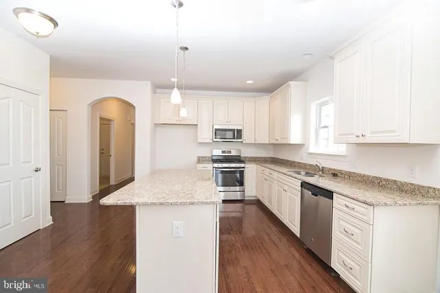 an empty room with chandelier fan and windows