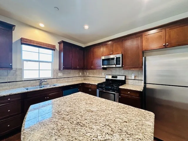 a kitchen with granite countertop a refrigerator stove top oven and sink
