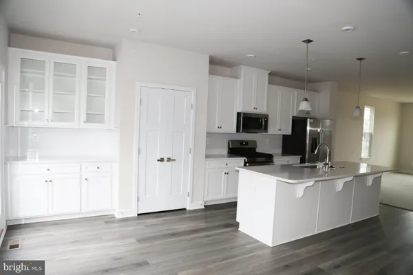 a kitchen with stainless steel appliances granite countertop a stove top oven a sink a refrigerator and white cabinets