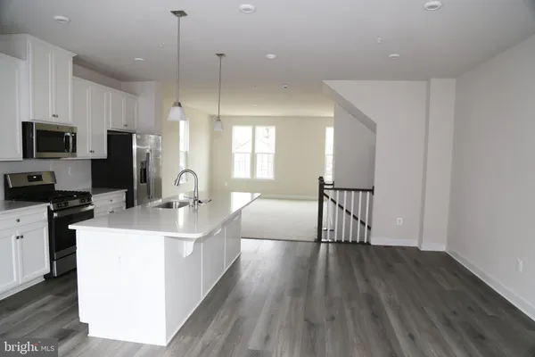 a large kitchen with stainless steel appliances a large counter top a sink a stove a refrigerator and a window