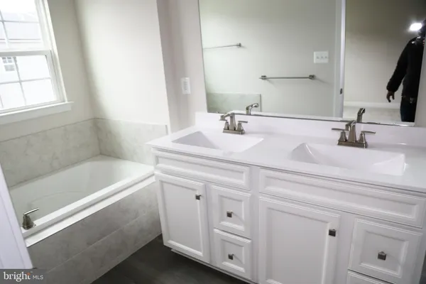 a bathroom with a sink tub vanity and a mirror