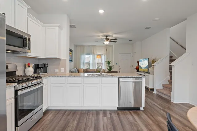 a kitchen with a sink wooden floor and stainless steel appliances