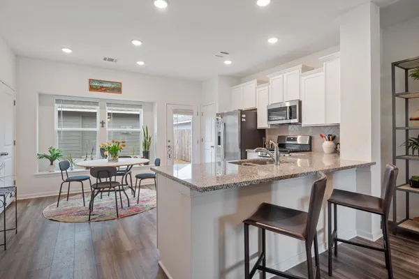 a kitchen with kitchen island granite countertop a dining table chairs and refrigerator