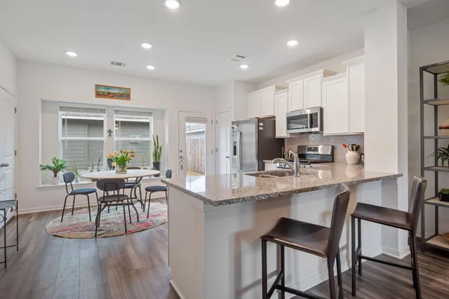 a kitchen with kitchen island granite countertop a dining table chairs and refrigerator
