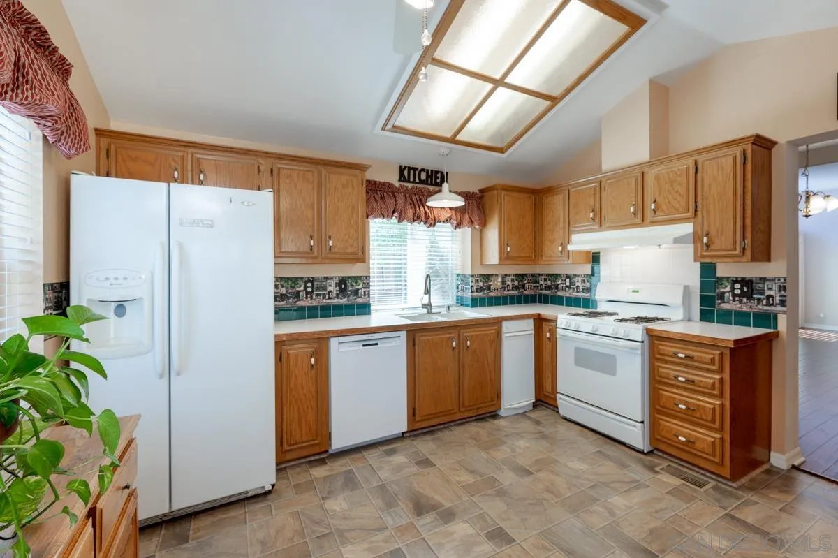 15935 Spring Oaks Road, Unit 122 El Cajon, CA 92021 - Photo 12 of 30 a kitchen with stainless steel appliances granite countertop a refrigerator a oven a sink with wooden cabinets and floor