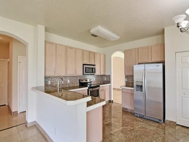 a kitchen with stainless steel appliances granite countertop a refrigerator a stove a sink and a refrigerator