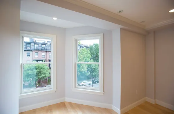 a view of an empty room with wooden floor and windows