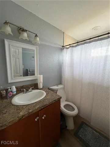 a bathroom with a granite countertop sink toilet a mirror and shower