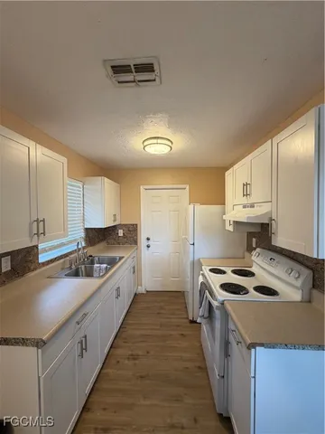 a large kitchen with stainless steel appliances granite countertop a sink stove and refrigerator