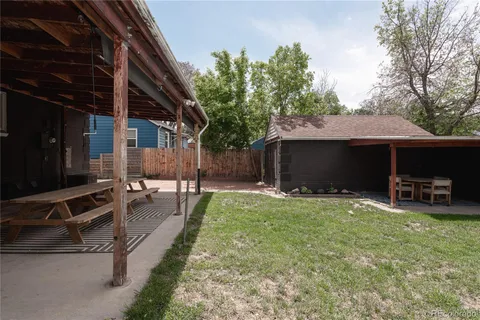 a view of a backyard with table and chairs under an umbrella with wooden fence