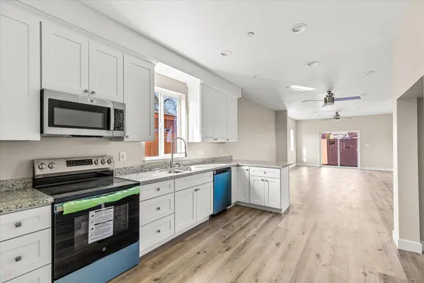 a kitchen with granite countertop a stove top oven a sink dishwasher and wooden cabinets