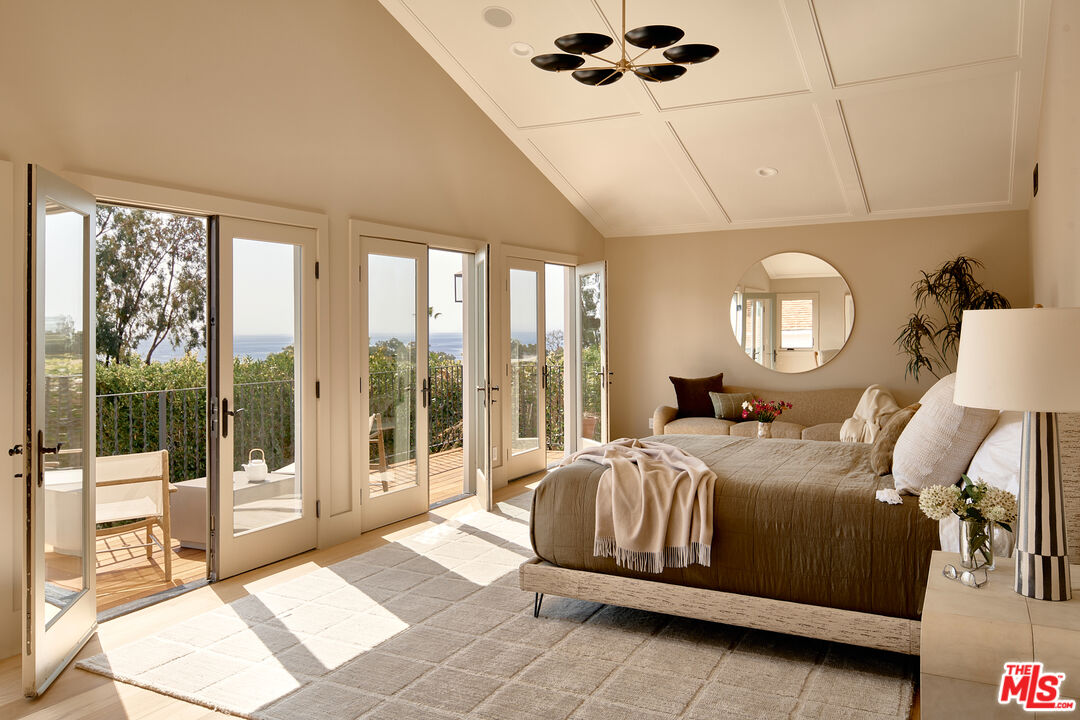 6930 Dume Drive Malibu, CA 90265 - Photo 20 of 34 a bedroom with a large bed and a chandelier