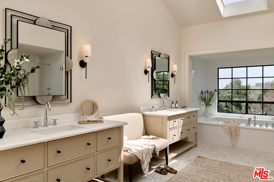6930 Dume Drive Malibu, CA 90265 - Photo 21 of 34 a spacious bathroom with a double vanity sink a large mirror and a bathtub