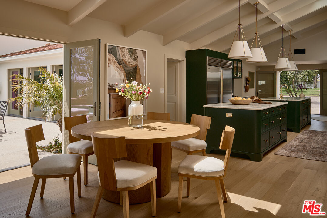 6930 Dume Drive Malibu, CA 90265 - Photo 9 of 34 a dining room with wooden floor a chandelier a glass table and chairs