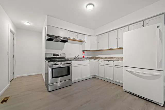 a kitchen with granite countertop white cabinets and white appliances