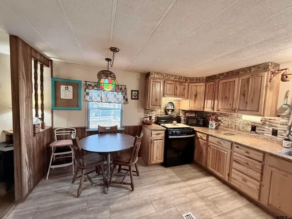 a kitchen with a stove a sink dishwasher a dining table and chairs with wooden floor