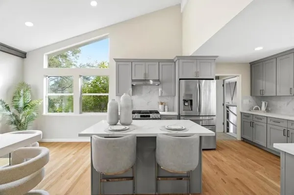 a kitchen with stainless steel appliances granite countertop a stove a refrigerator a sink a dining table and chairs