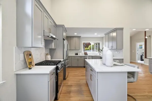 a kitchen with kitchen island a counter top space a sink stainless steel appliances and cabinets