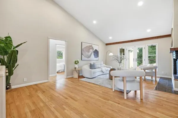 a living room with furniture large window and wooden floor