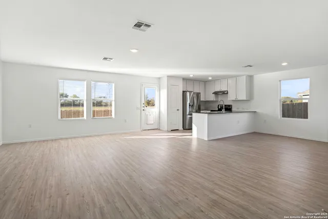 a view of an empty room with a window and wooden floor