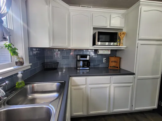 a kitchen with granite countertop a sink a stove and a microwave