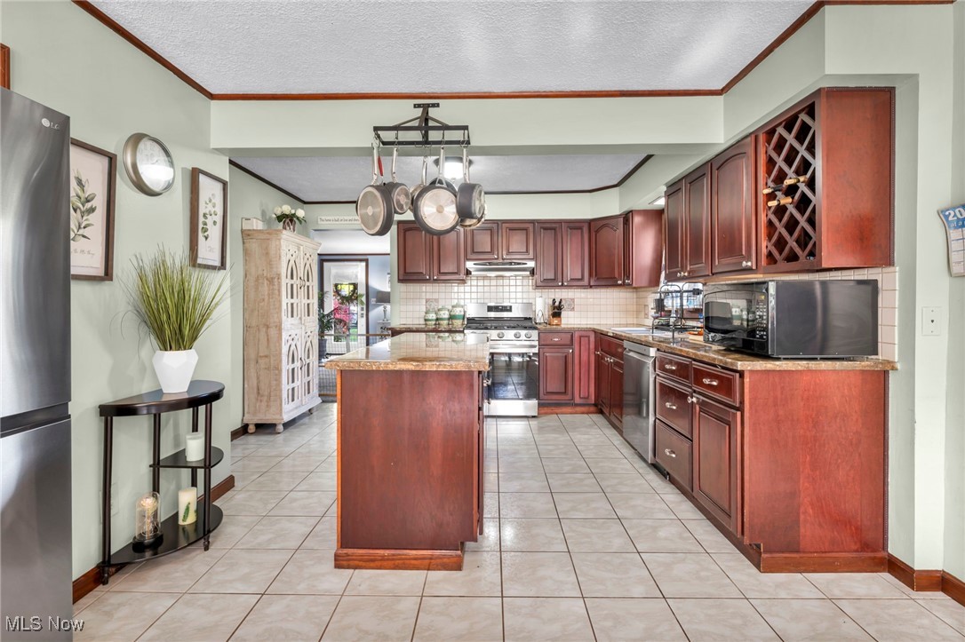 8164 Edgewood Road Mentor, OH 44060 - Photo 12 of 42 Kitchen with light tile patterned floors, stainless steel appliances, a textured ceiling, and a center island