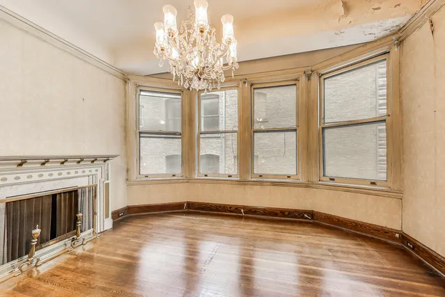 a view of an empty room with wooden floor fireplace and a window