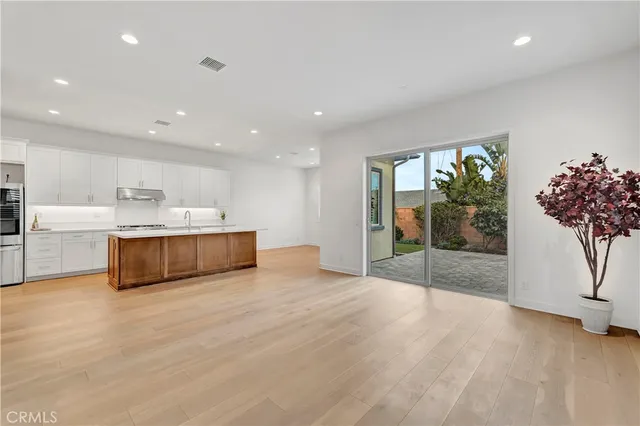 a large white kitchen with kitchen island a faucet a sink and a white cabinets