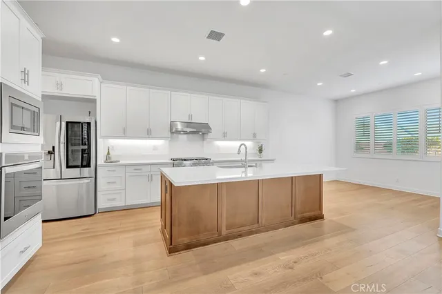 a kitchen with cabinets a sink stainless steel appliances and dining table