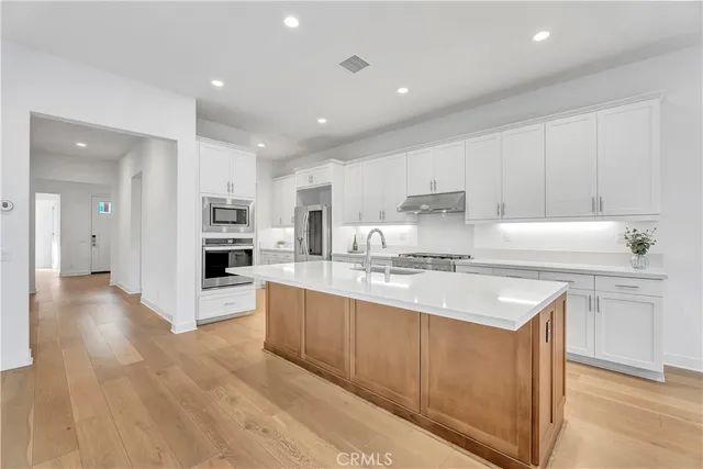 a large kitchen with stainless steel appliances a sink and a refrigerator