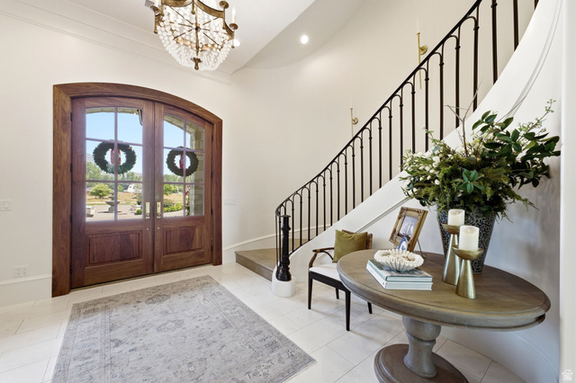 71 Farm Road Midway, UT 84049 - Photo 5 of 92 Grand entryway featuring a curved staircase with wrought iron balusters, a large arched wooden double-door entry with divided lites, and a crystal chandelier