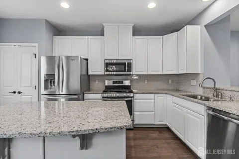 a kitchen with kitchen island granite countertop a sink stove and refrigerator