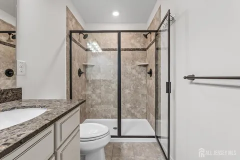 a bathroom with a granite countertop sink toilet and shower