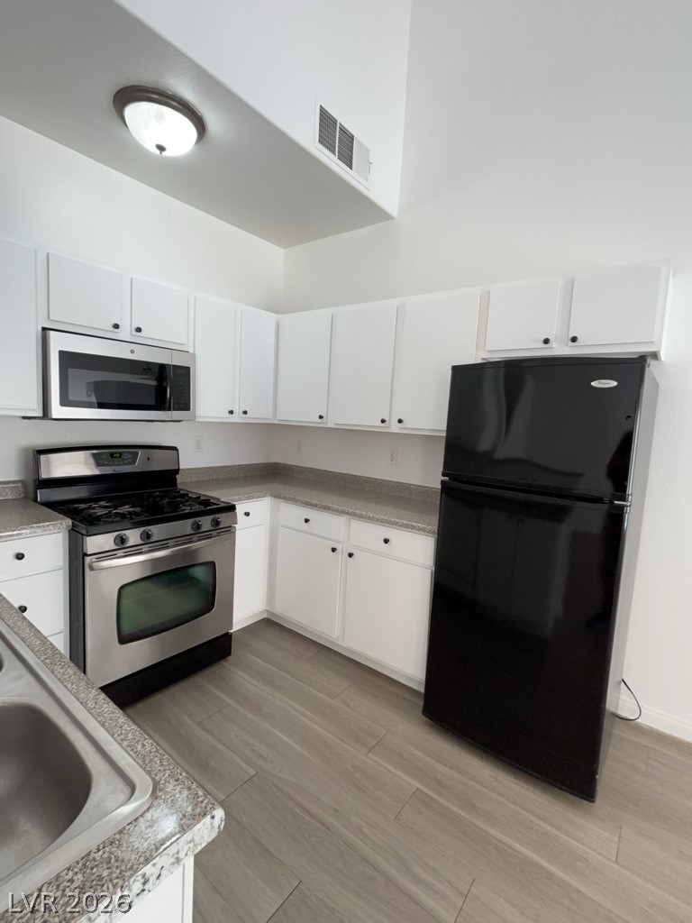 4915 East Russell Road, Unit 160 Las Vegas, NV 89120 - Photo 5 of 12 Kitchen with stainless steel appliances, white cabinets, light wood-style floors, and light countertops