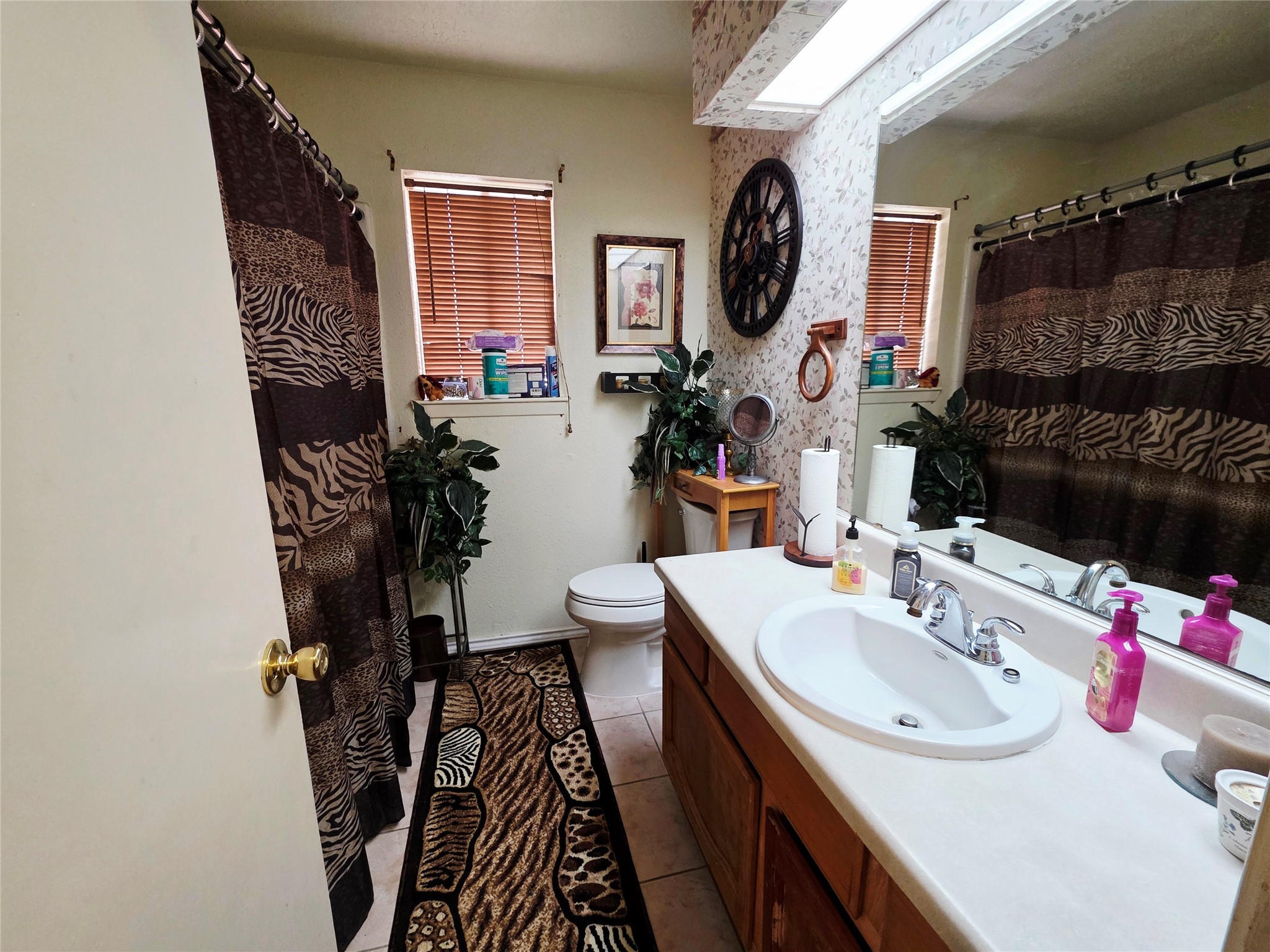 1323 Padstow Lane Channelview, TX 77530 - Photo 8 of 11 This bathroom features a single sink vanity with a large mirror, and shower/bath. It has two small windows with blinds for natural light.