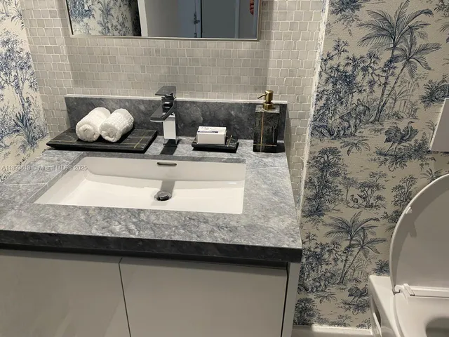 a bathroom with a granite countertop sink a toilet and shower