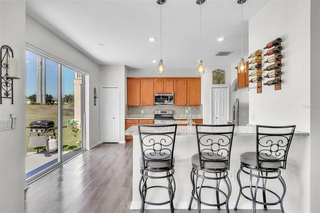 a kitchen with stainless steel appliances kitchen island granite countertop a stove a refrigerator and white cabinets with wooden floors