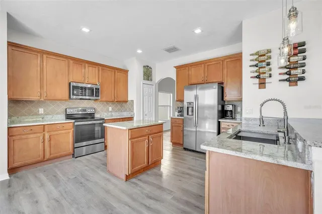 a large kitchen with stainless steel appliances granite countertop a stove a sink dishwasher and a refrigerator