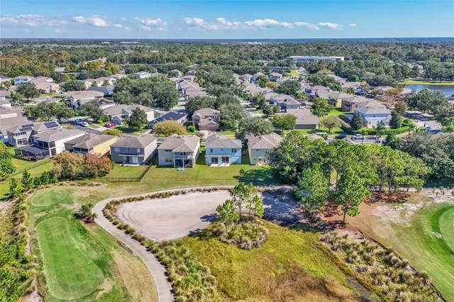 an aerial view of residential houses with outdoor space and trees