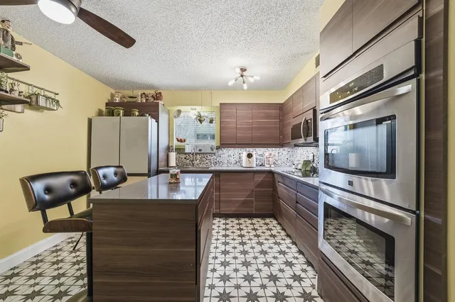 a kitchen with stainless steel appliances kitchen island granite countertop a sink and wooden cabinets