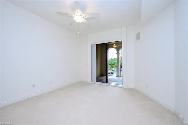 an empty room with a chandelier fan and windows