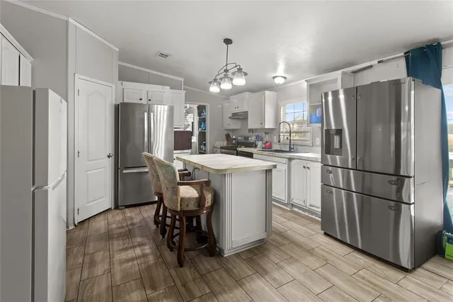 a kitchen with refrigerator a sink dishwasher a dining table and chairs