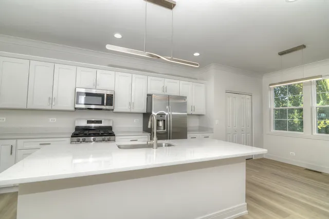 a kitchen with stainless steel appliances a sink a stove a microwave a center island and cabinets