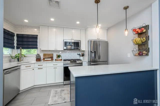 a kitchen with stainless steel appliances granite countertop a refrigerator a sink dishwasher a oven a dining table and chairs with wooden floor