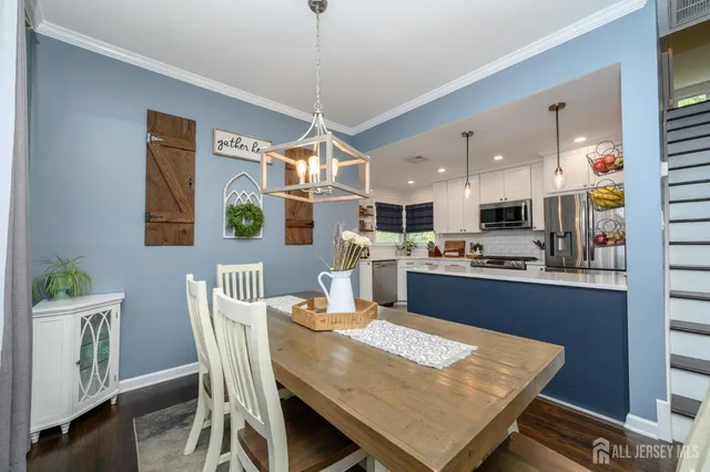 a kitchen with stainless steel appliances granite countertop a sink a stove a refrigerator cabinets a dining table and chairs