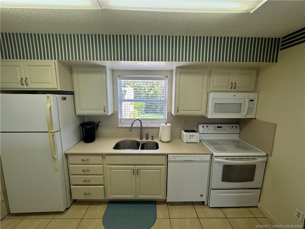 1501 Northeast Ocean Boulevard, Unit 9 Stuart, FL 34996 - Photo 21 of 41 a kitchen with a sink a refrigerator and cabinets
