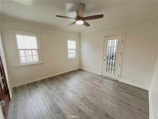 a view of an empty room with a window and wooden floor
